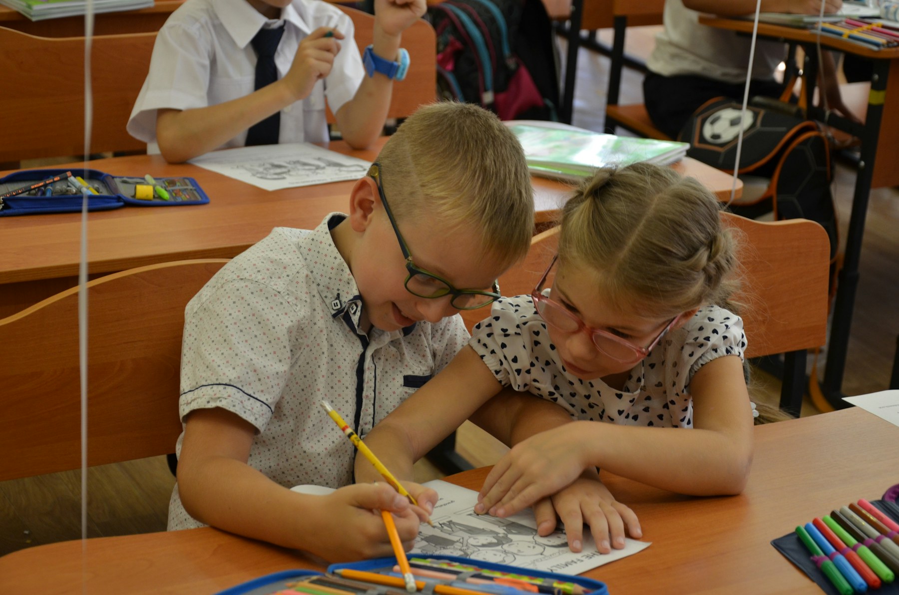 Two young classmates work together on a drawing.